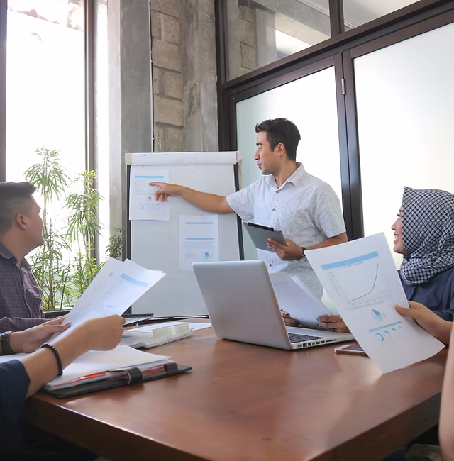 Business team discussing data charts during a leadership workshop in a bright room.