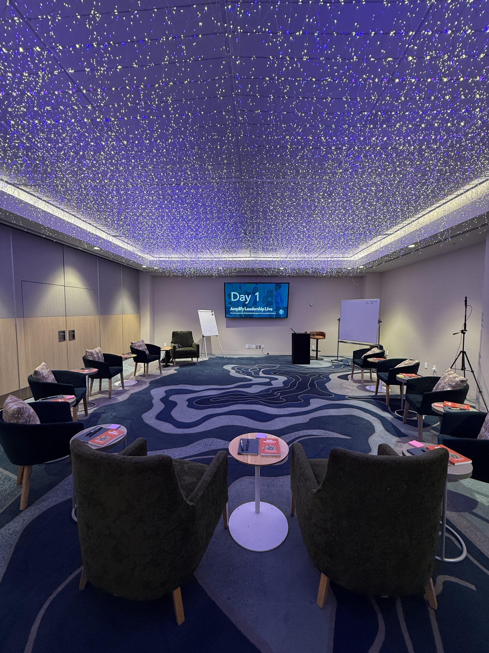 Amplify Leadership Live workshop room setup with round seating and starry ceiling lights.